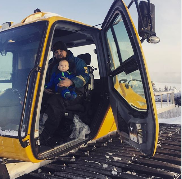 A man and child in the cab of an excavator.